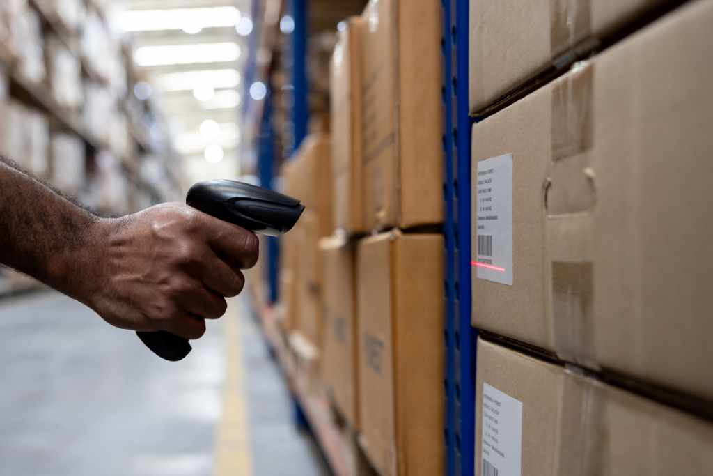 a warehouse manager using inventory tracking software and a barcode scanner