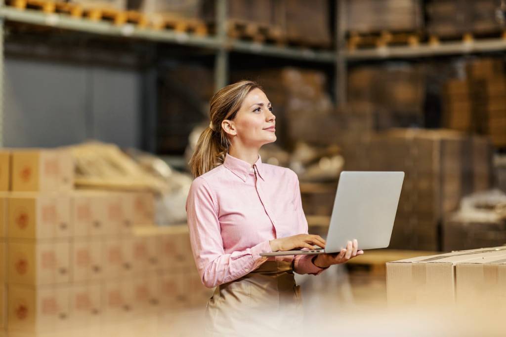 Woman taking stock on laptop in warehouse
